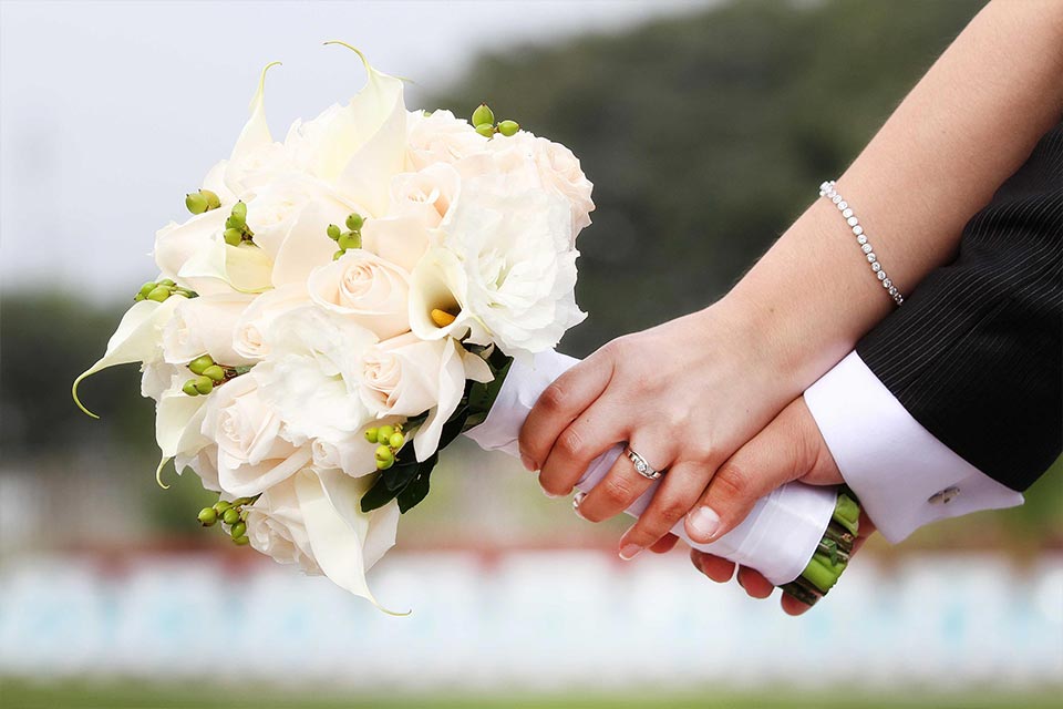 Detalle-de-manos-de-novios-sosteniendo-un-ramo-de-rosas-blancas-y-calas-mostrando-el-anillo-de-bodas.-Fotografo-de-bodas-en-Chia