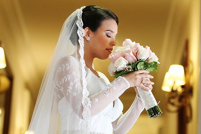 Primer-plano-de-novia-sosteniendo-un-ramo-de-rosas-blancas-y-rosadas-luciendo-un-vestido-de-encaje-y-velo-detallado-en-una-boda-en-Chia