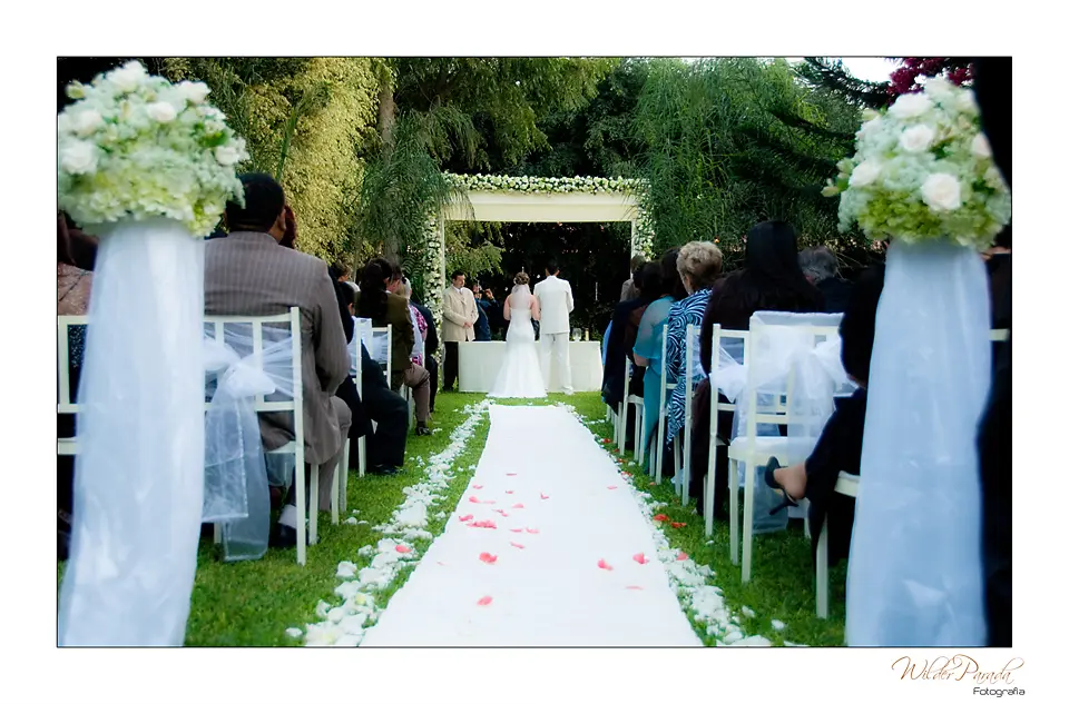 Una vista panorámica del pasillo central decorado con flores y el altar al fondo, con invitados a los lados.
