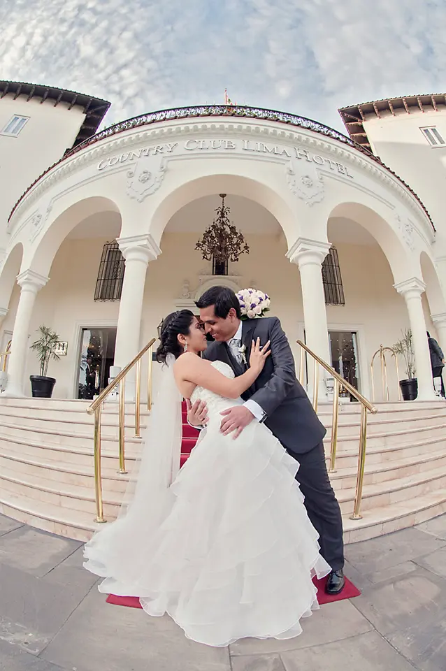 Fotografía creativa con lente ojo de pez de los novios posando en la fachada del Country Club Hotel, con el novio inclinando a la novia.