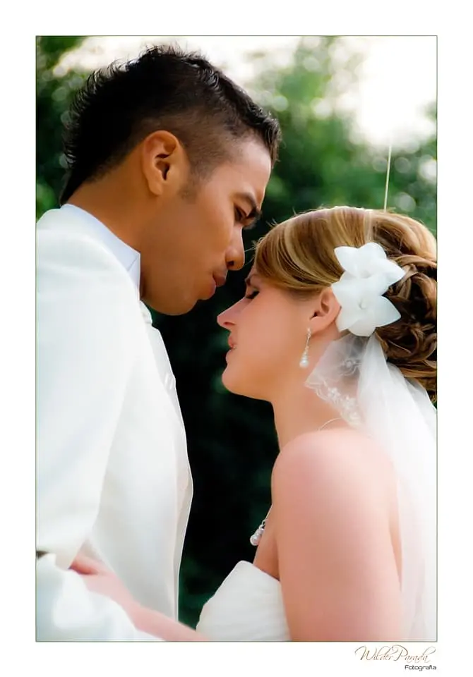 Primer plano de perfil de los novios compartiendo un momento íntimo, destacando el tocado de flores blancas y el velo en el peinado de la novia.