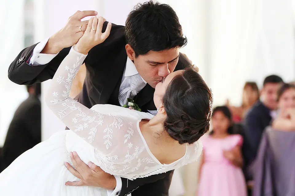 El novio inclina sutilmente a la novia para darle un beso apasionado en la pista de baile, mostrando las argollas matrimoniales en primer plano en chia. Wilder fotografia