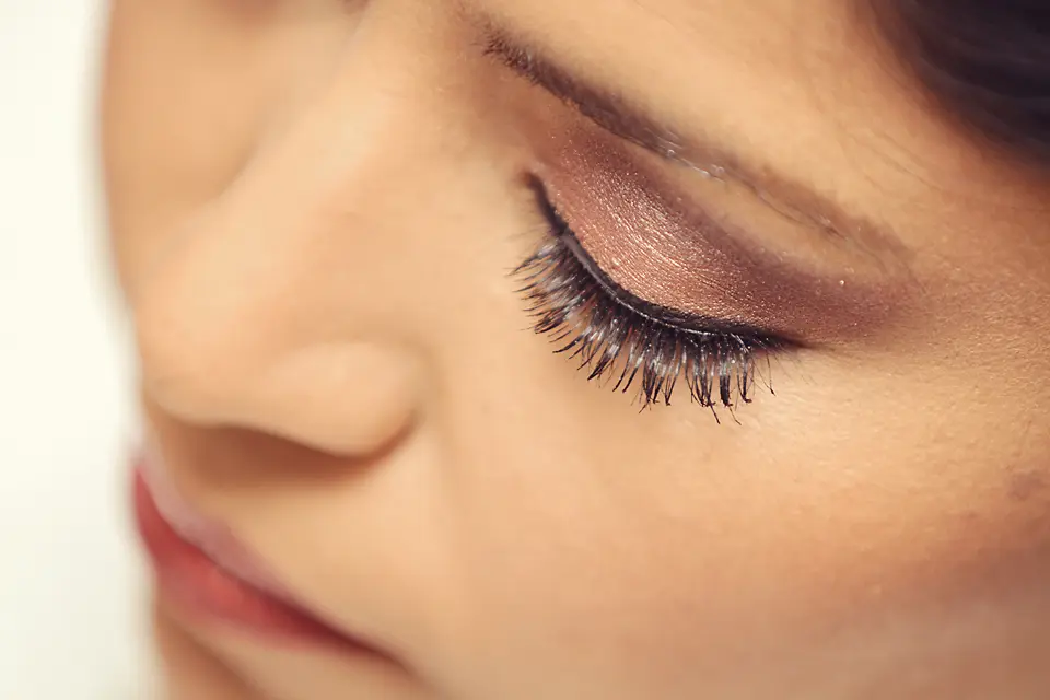 Macrofotografía del maquillaje de ojos de una novia en tonos tierra y bronce con pestañas largas y definidas durante su preparación