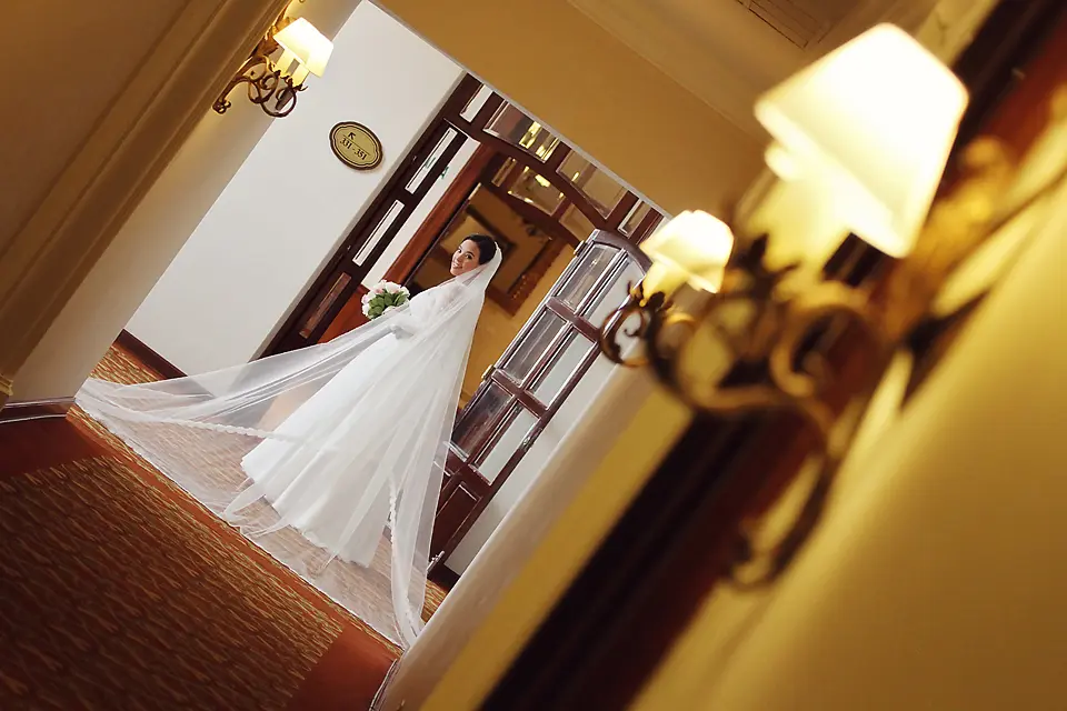 Retrato artístico de novia con velo largo extendido en el pasillo de un hotel, sesión de fotos de bodas en la Sabana de Bogotá.