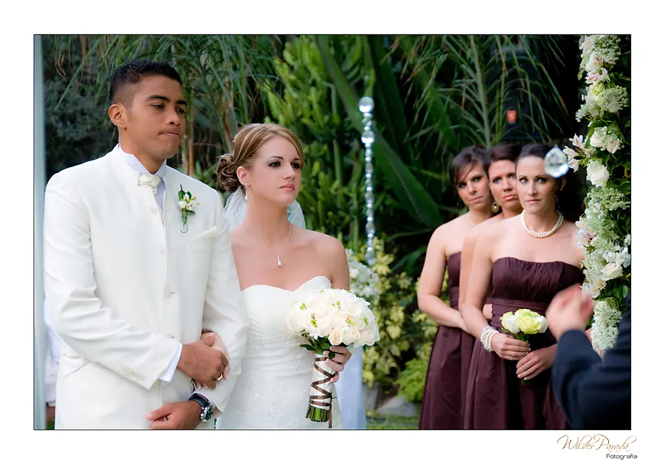 Composición de fotografía de boda en Chía con los novios en primer plano y las damas de honor al fondo durante la ceremonia.