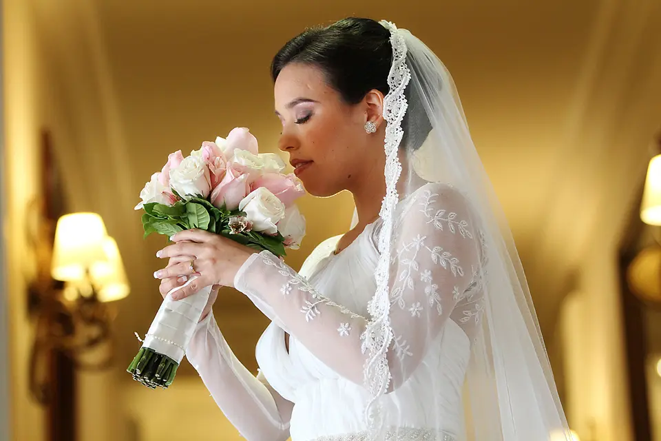 Novia con los ojos cerrados oliendo su ramo de rosas rosadas y blancas, fotografía de bodas romántica y emotiva en Chía.